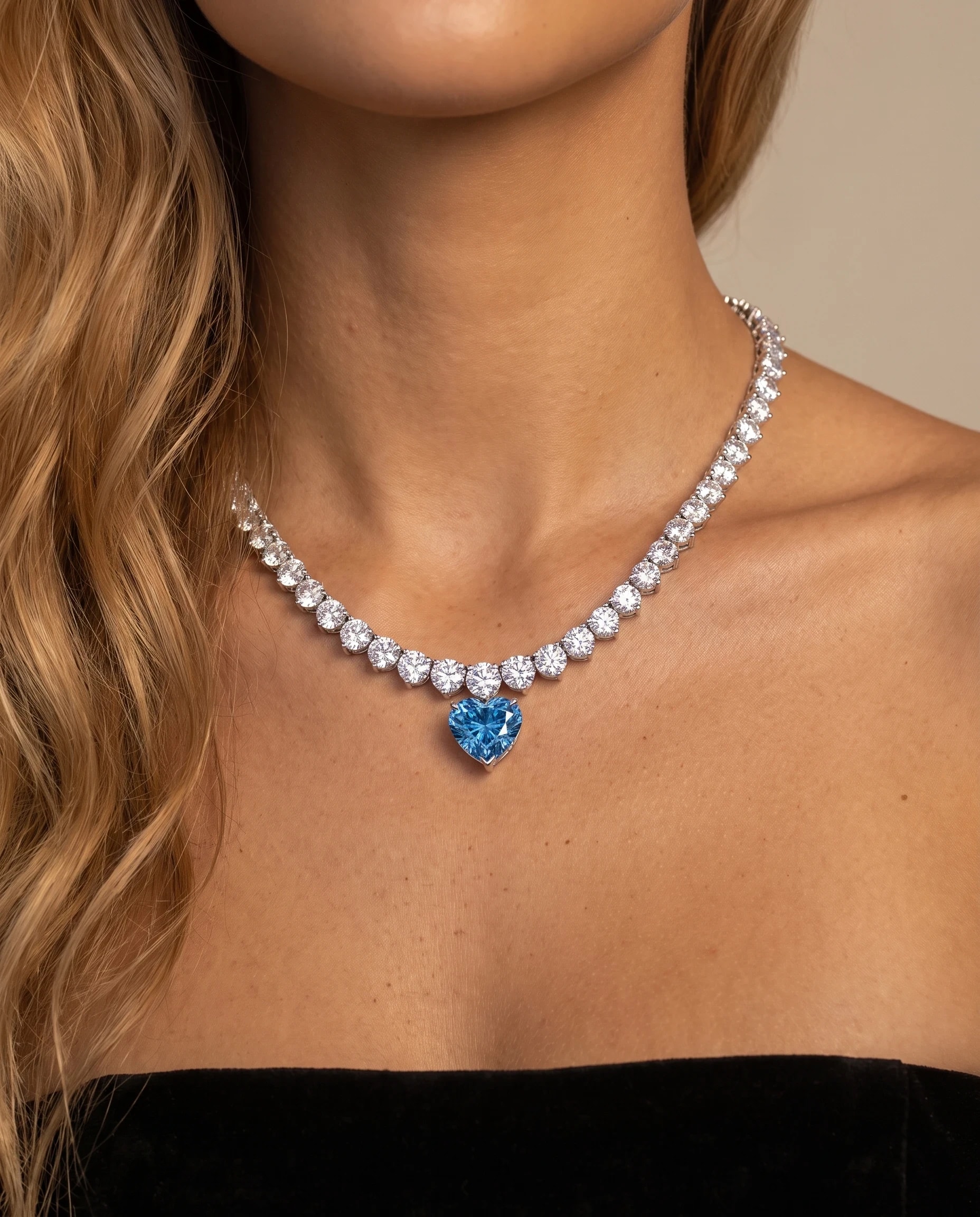 The necklace worn above a black strapless top, the blue heart resting just below the collarbone
